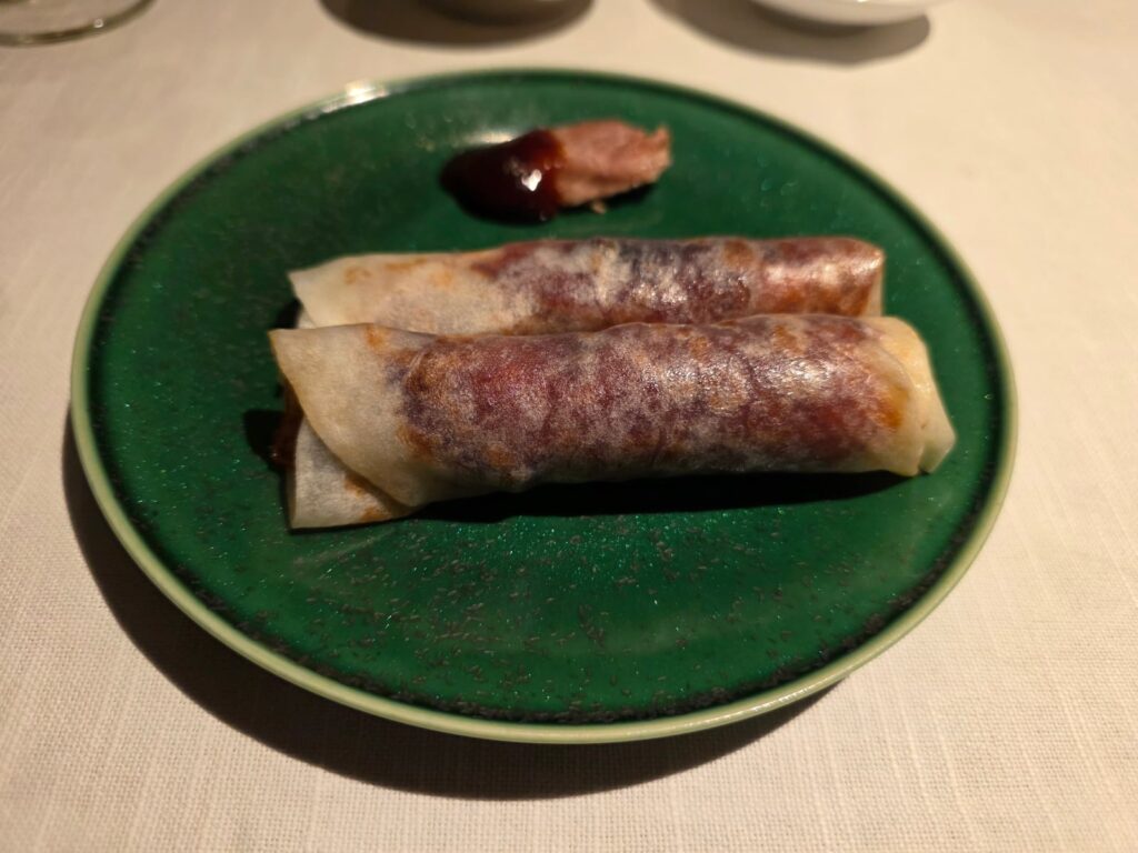 六本木「中國飯店」の北京ダック。薄皮で包んだ2本が緑の皿に並ぶ。